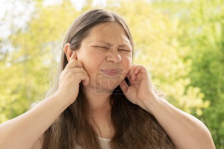 caucasian mature woman holds painful ear, hearing loss, face close-up, medical concept, hearing control, middle ear inflammation, otitis media