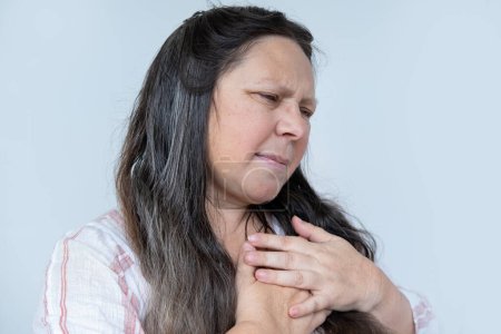 mujer madura caucásica experimenta dolor torácico repentino detrás del esternón, agarrar el pecho, hipertensión arterial, miocarditis o arritmia, experiencias de enfermedades del corazón, factores de riesgo