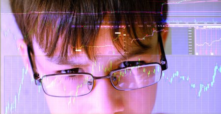 Intelligentes 12-jähriges Kind, Junge mit Brille studiert aufmerksam Börsendiagramme auf Computerbildschirm und zeigt potenzielle junge Finanzhändler, die Zukunft des Finanzwesens, Finanzkompetenz