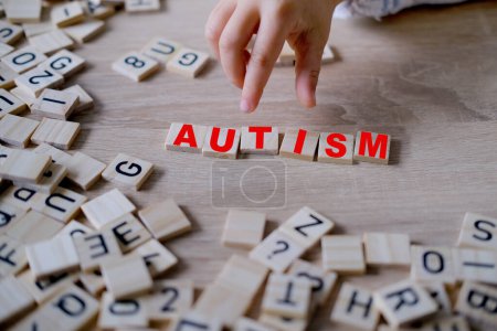 main de l'enfant mot complet "AUTISM", symbolisant l'importance du diagnostic précoce et de l'intervention pour les enfants autistes, l'acceptation de soi et embrassant la neurodiversité
