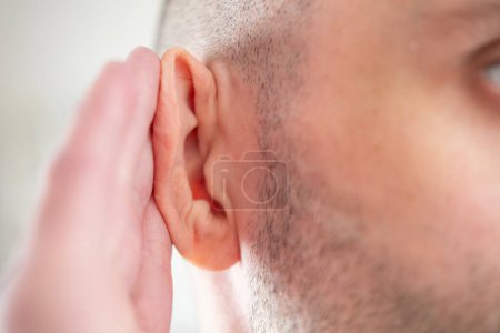 Young man clutches ear in pain, suffering from severe earache, hearing loss, Ear Discomfort, Hearing Test, Acute Otitis Media, Treatment and Care