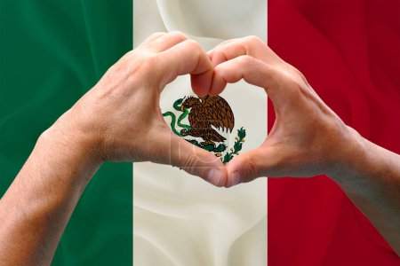 Nahaufnahme männlicher Hände in Herzform vor dem Hintergrund der seidenen Nationalflagge Mexikos, Patrioten des Länderkonzepts, Unabhängigkeitstag, Reisen, internationale Zusammenarbeit