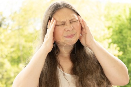 diseased mature woman experiences severe headache, holding head, Hot flashes during menopause, Decreased memory and concentration, feeling nervous, tired, exhausted, menopause