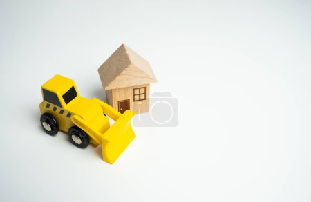 Photo for Bulldozer and house. Demolition services, land leveling and other land works for construction. Encroachment on private property. Illegal buildings. Violation of building codes. Housing renovation. - Royalty Free Image