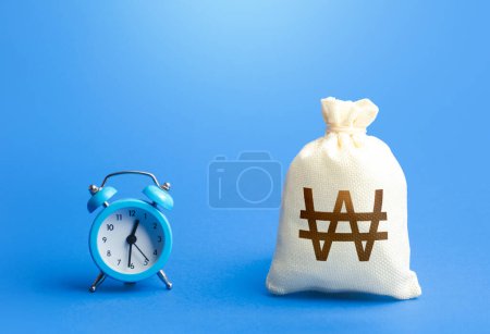 Photo for Time and south korean won money bag. Loans, mortgages. Deposits, savings. Retirement funds. Bank, finance. Investments. Hourly pay. Time of payment in the contract. Taxation. Bonds, dividends. - Royalty Free Image