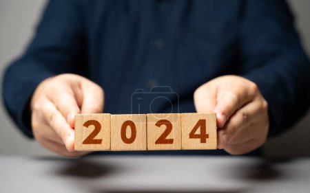 Mann hält Block mit 2024. Der Beginn eines neuen Jahres. Neue Trends annehmen, Prognosen erstellen, Pläne für das kommende Jahr aufstellen. Rückblick auf vergangene Errungenschaften und Erfahrungen, Blick nach vorn