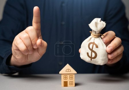 Photo for Financial adviser warns about buying real estate. Man with attention sign holding dollar money bag. Becoming a homeowner. Choosing the best mortgage loan terms for real estate purchase. - Royalty Free Image
