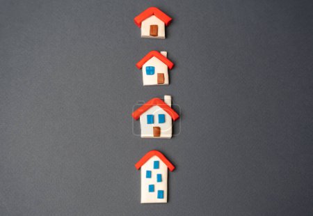 Téléchargez les photos : Figurines maisons dans une rangée. Trouver les options de logement les plus appropriées. Offres sur le marché immobilier. Services immobiliers. Hypothèque. Évaluation des bâtiments résidentiels. Achat et vente. - en image libre de droit