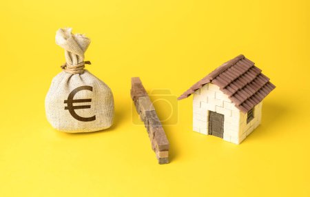 Téléchargez les photos : La maison et le sac d'argent en euros sont séparés par une barrière. Arrêtez de surchauffer le marché immobilier. L'investissement comme menace de créer une bulle de marché. L'afflux de capitaux. Des niveaux d'endettement élevés, - en image libre de droit