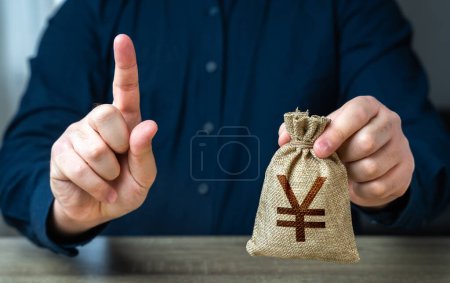 Photo for A man warns about the terms of a transaction or borrowing money. Gesture of attention and chinese yuan or japanese yen money bag. Bad credit history. Funding and grants. Banks and finance. - Royalty Free Image
