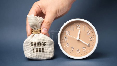 Photo for Money bag Bridge loan and clock. Short-term loan used until a person or company secures permanent financing. Business and finance concept - Royalty Free Image
