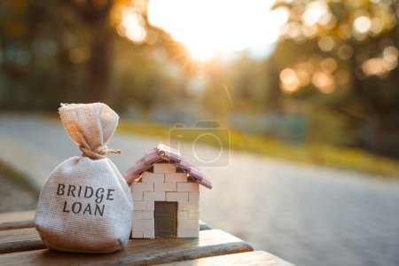 Überbrückungskreditkonzept - ist ein kurzfristiges Darlehen, das durch Immobilien besichert ist.Geldsack und Miniaturhaus im Park im Sonnenuntergang. Immobilien und Finanzen