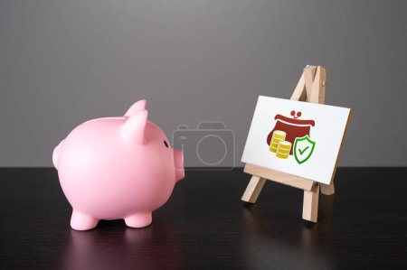 Photo for The piggy bank looks at guaranteeing the safety of savings. Deposits and savings. Loans and credits, mortgage. Economics and currency exchange, stock market. Funding and grants. - Royalty Free Image