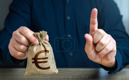 Photo for A man warns with his finger offering a euro money bag. Bad credit history. Funding and grants. Banks and finance. Terms of borrowing money. Strict conditions. Loan for a specific purpose. - Royalty Free Image