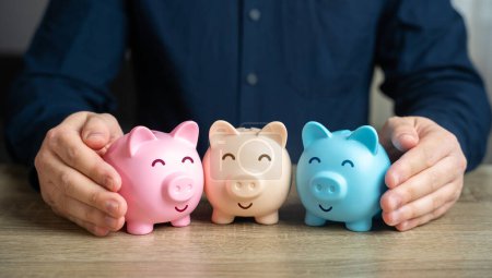 Photo for A man puts together piggy banks. Create your investment portfolio. Manage assets. Bank deposits and savings. Diversification of investments. Store and accumulate funds. - Royalty Free Image