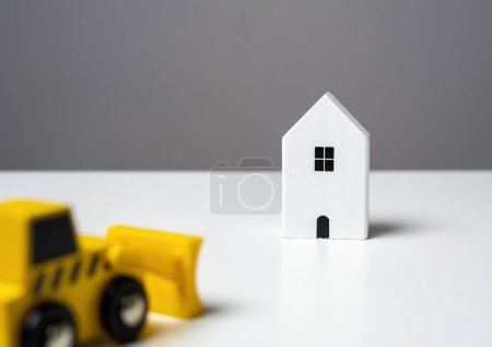 Photo for Bulldozer is about to demolish a house. Illegal buildings construction. Plan for the renewal and restoration of residential areas. Lawsuit. Illegal construction or demolition of a building. - Royalty Free Image