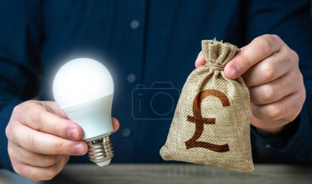 Foto de Libra esterlina británica bolsa de dinero y la quema de bombilla idea en las manos de un hombre. Inversión en una idea. Ofrecer incentivos financieros para mejorar la eficiencia energética. Reducir la huella de carbono - Imagen libre de derechos