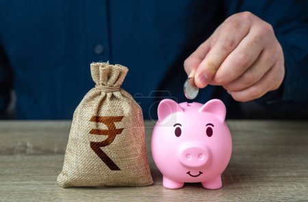 Photo for Pig piggy bank and indian rupee money bag. Banks and finance. Savings and accumulation of funds from cutting expenses. Investments, fundraising. Savings management. - Royalty Free Image
