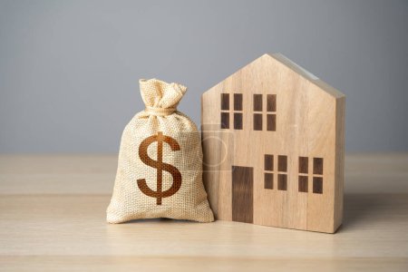 Wooden house and dollar money bag. Property Insurance. Taxes. Buying and selling real estate. Housing prices. Property value appraisal. Make a deal.