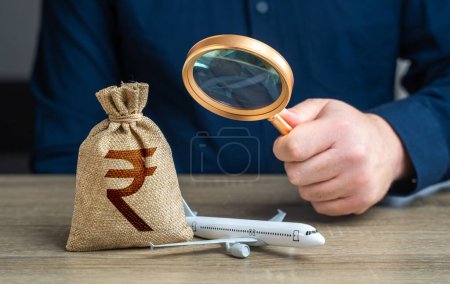 Airplane and indian rupee money bag under investigation. Economic impact of aviation industry. Payment of taxes, fees and excise taxes. Measure impact on local economy. Environmental footprint.