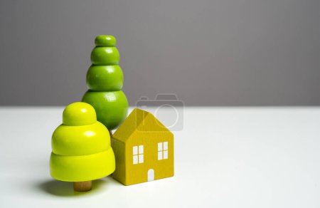 House and green trees. Environmental friendliness and harmony with nature. Eco house. Autonomy and closeness with nature. Wooden figures