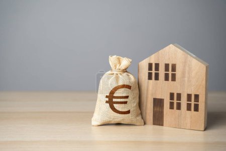 Wooden house and euro money bag. Taxes. Buying and selling real estate. Housing prices. Property value appraisal. Make a deal. Property Insurance.