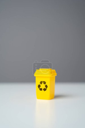 Yellow recycling bin on gray background. Selling recycled material or getting grants for green projects. Circular economy. Conserve natural resources, reduce waste, create jobs in recycling industry.