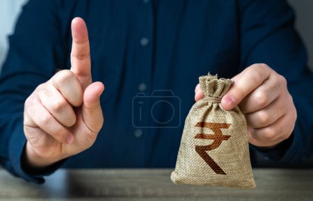 Photo for A man warns with his finger offering a indian rupee money bag. Funding and grants. Banks and finance. Bad credit history. Strict conditions. Loan for a specific purpose. Terms of borrowing money. - Royalty Free Image