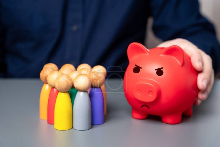 A businessman holds a red piggy bank next to a group of people figures. Lack of budget funds. Poor deposit conditions. Problems with pensions and savings systems.