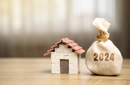 Money bag 2024 and miniature house. Family budget planning for next year. Mortgage rates and credit. Real estate fund concept. Refinance home.