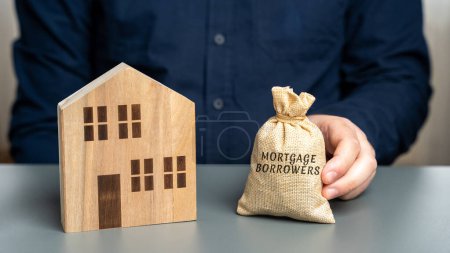 Concepto de prestatarios hipotecarios. Individuos o entidades que han tomado un préstamo hipotecario de un prestamista para financiar la compra de una propiedad. Bolsa de dinero y casa en miniatura