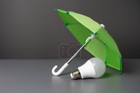 Una idea de bombilla bajo el paraguas del seguro. Soluciones innovadoras. Seguro de negocios. Protección de los derechos de autor, patentes y tecnologías.