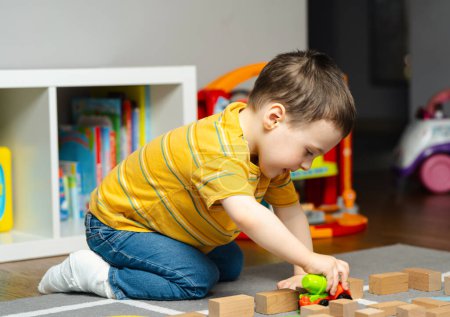 El niño pequeño con un vendaje o un yeso en la pierna juega con juguetes y bloques. La fractura del pie y el dedo en los niños. Salud humana y concepto de medicina