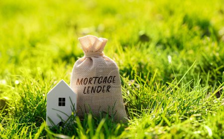 Mortgage lender money bag and house in a grass. Financial institution or mortgage bank that offers and underwrites home loans. Money and real estate finance concept.
