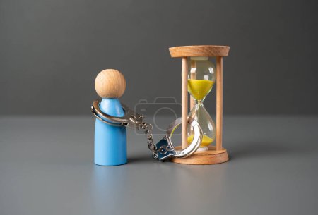 Un hombre está esposado a un reloj de arena. El concepto de limitación del tiempo de vida o privación. Ten paciencia. Estar limitado en el tiempo.