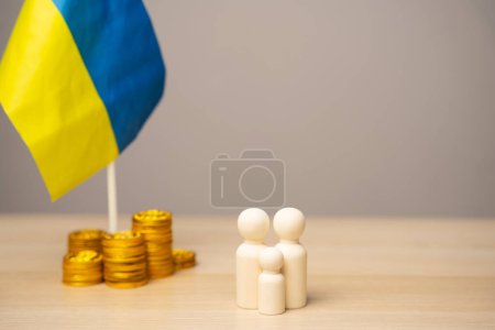 El concepto de ayudar a los residentes ucranianos afectados por la guerra. Apoyo financiero y donación. Economía, finanzas y fondos. Figuras familiares cerca de la bandera ucraniana con monedas