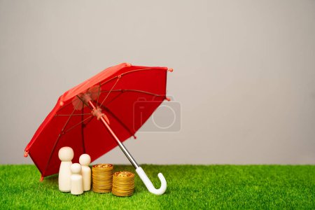 Familienfiguren mit Münzen stehen unter einem roten Regenschirm. Versicherungskonzept für Sach-, Lebens-, Kranken- und Finanzversicherungen. Stiftungspolitik. Finanzielle Absicherung