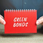 Green bonds concept. Type of fixed-income financial instrument to raise capital for projects and activities that have positive environmental and climate benefits. Notes in the hands of a businessman