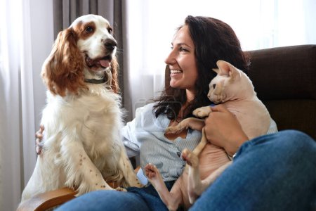 Eine Frau liegt mit Hund und Katze auf einem Sofa. Konzept Liebe zu Haustieren.