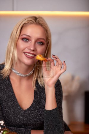 Foto de A woman with her hands eats a large appetizing shrimp. Selective focus - Imagen libre de derechos