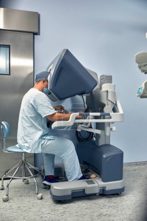 Foto de El cirujano en la cabina de control del robot cirujanos. Cirugía robótica en el momento del control de la máquina por el cirujano. - Imagen libre de derechos