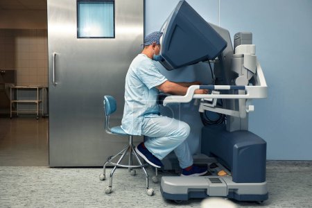 Photo for The surgeon is at the computer robot in a special control module, the medical robot is under the control of the doctor at a distance through the monipulator. Robotic surgery without incision - Royalty Free Image