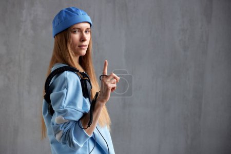 Téléchargez les photos : Portrait à mi-longueur d'une jeune fille aux cheveux longs, vêtue d'un pull bleu et coiffée d'un casque DJ sur l'épaule. Musique, amusement et beauté. Espace de copie - en image libre de droit