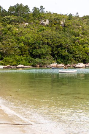 Foto de Playa con barco, arena, piedras y bosque en Governador Celso Ramos, Santa Catarina, Brasil - Imagen libre de derechos