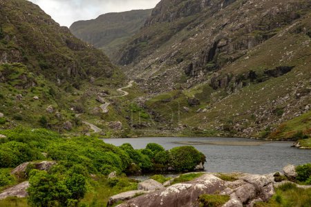 Téléchargez les photos : Lac, route et montagnes à Gap of Dunloe avec rochers et végétation, Killarney, Kerry, Irlande - en image libre de droit