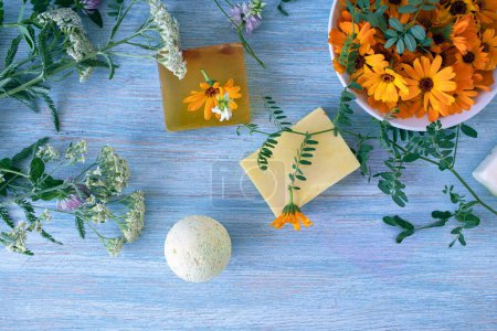Seife mit Ringelblumen, frischen Blumen und nützlichen Pflanzen, auf Holzgrund, Naturkosmetik, Körperpflege und Badeprodukte