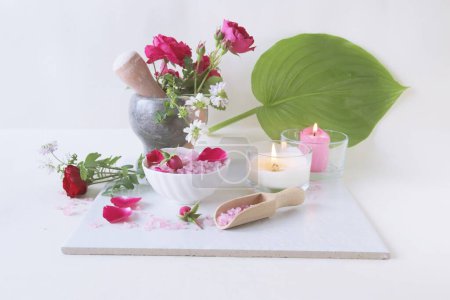 Spa still life with rose petals, salt and flowers on a white background