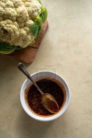 Téléchargez les photos : Procédé de cuisson du chou-fleur rôti, bol d'huile mélangée et d'épices, vue de dessus - en image libre de droit