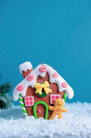 Christmas festive greeting card, mock up, ginger bread house ornament, snow on blue background with copy space for text