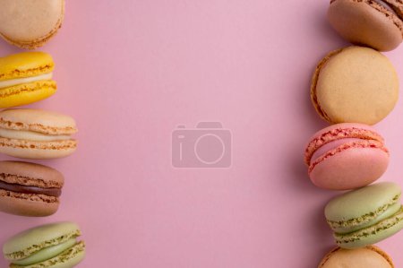 Foto de Galletas de colores macarrones. Macarons dulce postre francés, vista superior, fondo rosa - Imagen libre de derechos